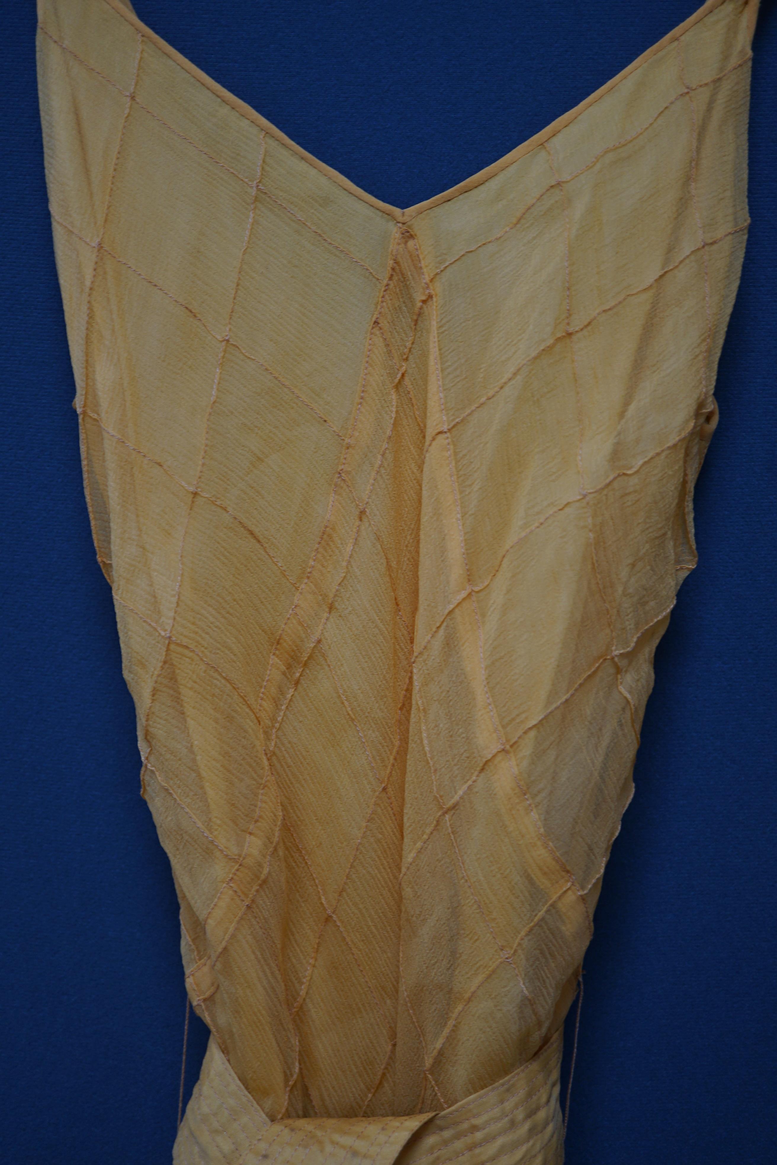 A 1930’s Harrods labelled saffron silk chiffon evening dress and jabot, lined in the same coloured taffeta, the dress kipper shaped with thin camisole straps and the chiffon sewn on the bias in diagonal seams finished wi